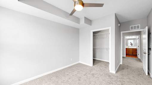 A room with a ceiling fan and carpeted floor.