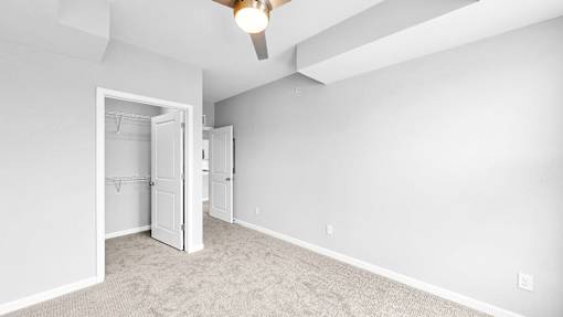 A room with a ceiling fan and a doorway leading to another room.