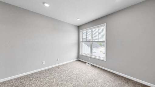 A room with a window and a carpeted floor.