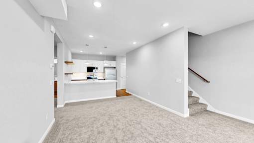 A spacious, empty room with a staircase on the right side.