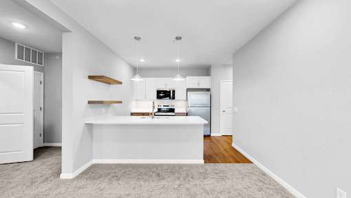 A white kitchen with a white island and a white fridge.