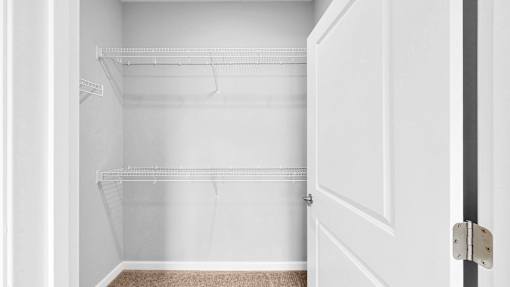 Empty white closet with a door open.