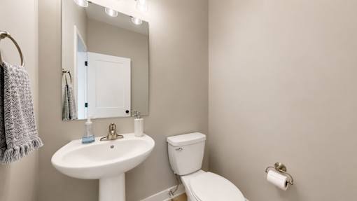 A white sink and toilet in a bathroom with a mirror above it.