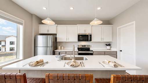 A modern kitchen with a large island and wooden chairs.