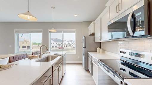 A modern kitchen with a refrigerator, oven, and sink.