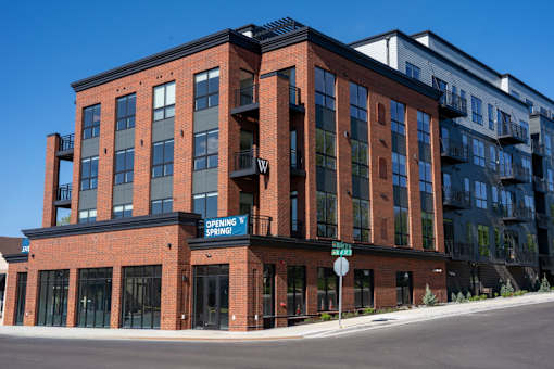 A red brick building with a blue sign that says "Opening Spring".