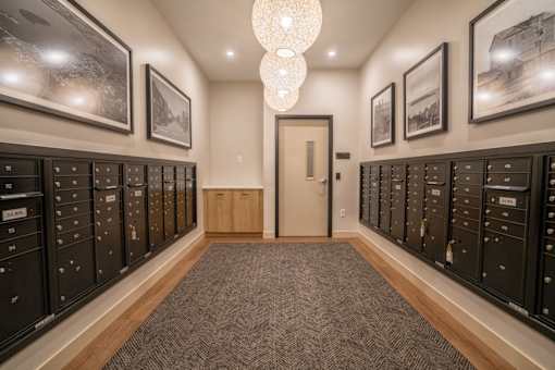 A hallway with a carpeted floor, a chandelier, and a door at the end.
