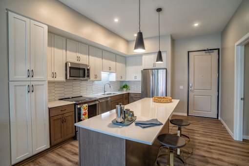 A kitchen with a white counter top and a large island.