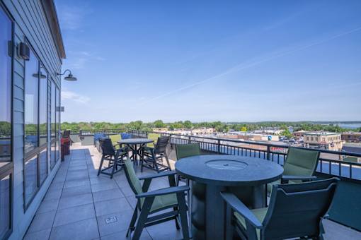 A balcony with a table and chairs overlooking a cityscape.