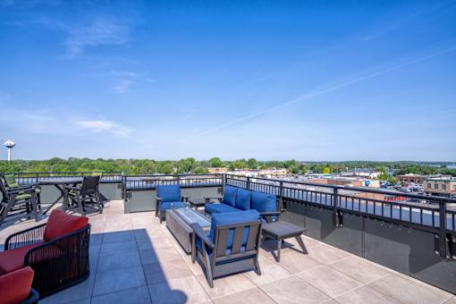 A rooftop patio with blue cushioned seating and a view of the city.