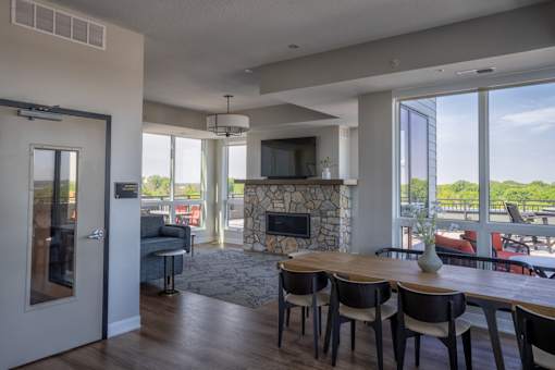 A modern living room with a stone fireplace and a dining table set for four.