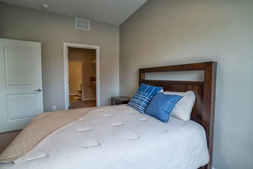 A bed with a white comforter and blue pillows in a room.