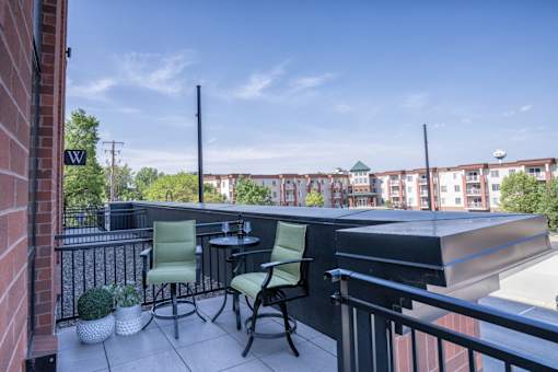 A balcony with a table and chairs overlooking a cityscape.