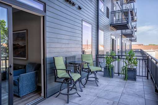 A balcony with a table and chairs.