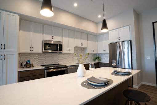 A modern kitchen with a white countertop and stainless steel appliances.