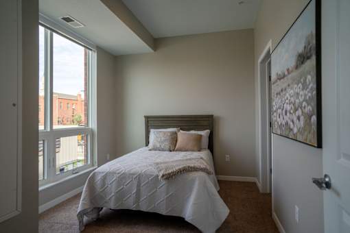 A bedroom with a large bed and a window overlooking a city.