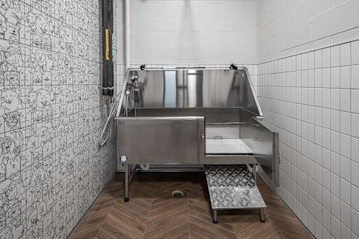A stainless steel sink in a tiled room with a wooden floor.