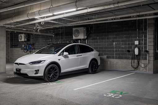 A white Tesla car is parked in a charging station.