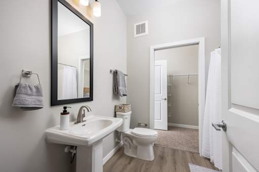 A white bathroom with a sink, toilet, and mirror.