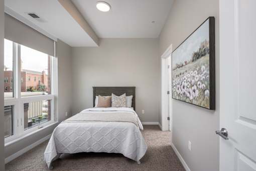 A bedroom with a large bed and a painting on the wall.