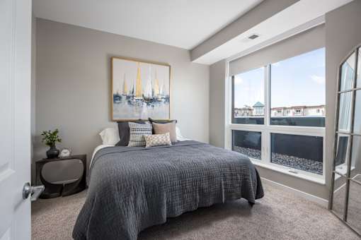 A bedroom with a large bed and a painting of sailboats on the wall.