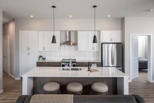 A modern kitchen with a bar stool and a fridge.