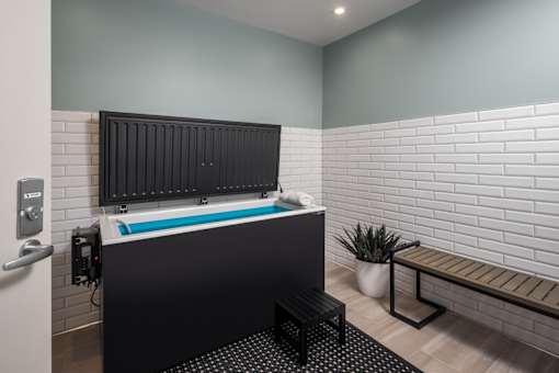 A modern bathroom with a black tub and a bench.