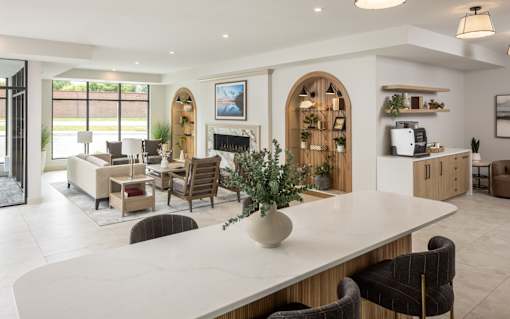 A modern living room with a large white table and brown chairs.