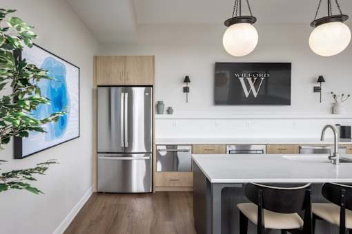 A kitchen with a fridge, sink, and a painting on the wall.