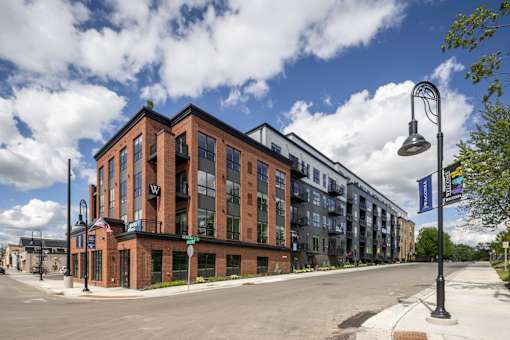 A street view of a building with a blue sky and clouds in the background.