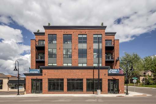 A red brick building with a black awning that says "LEASING" on it.