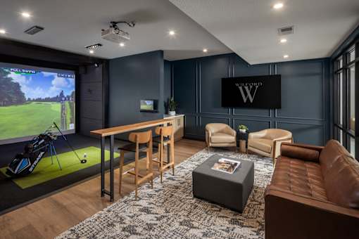 A modern living room with a golf simulator and a large TV.