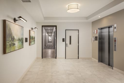 A hallway with a white wall, a painting, and two doors.