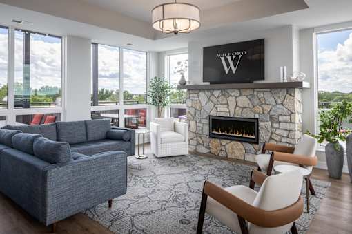 A living room with a stone fireplace and a flat screen TV mounted above it.