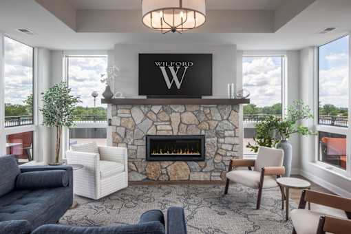 A living room with a stone fireplace and a large window.