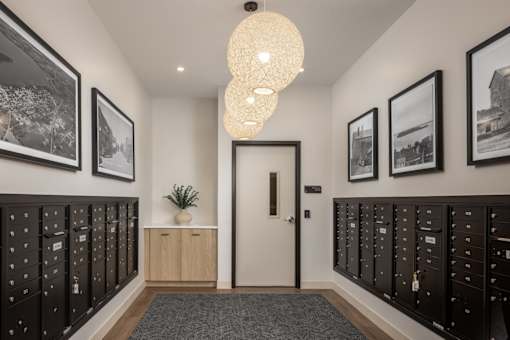 A hallway with a white door, black lockers on both sides, and pictures on the wall.