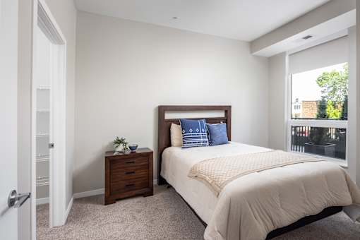 A bedroom with a bed, nightstand, and window.