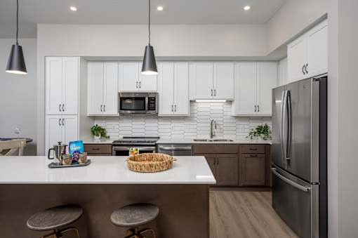 A modern kitchen with white cabinets and a stainless steel refrigerator.