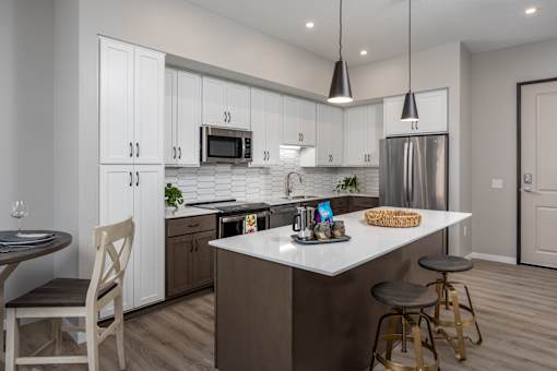 A kitchen with a white island and a stainless steel refrigerator.