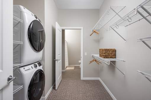 A laundry room with a washer and dryer on the left and a walk-in closet on the right.