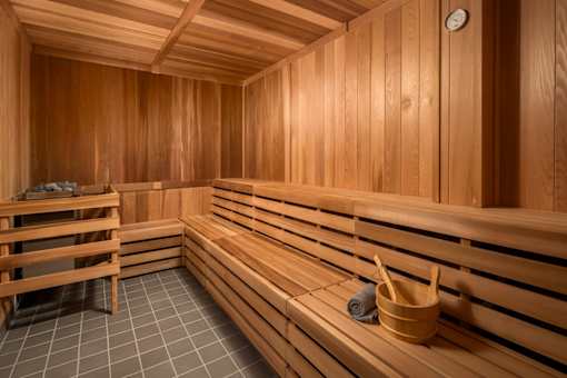 A wooden sauna with benches and a bucket of stones.