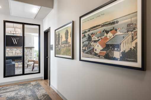 A hallway with a rug and two framed pictures on the wall.