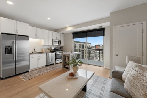 a living room with a kitchen and a sliding glass door to a balcony