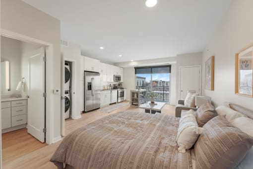 a bedroom with a couch and a bed and a kitchen with a window