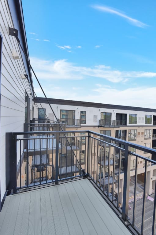 a balcony with a black railing and a white building in the background