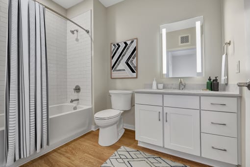 a bathroom with white cabinets and a white and black shower curtain