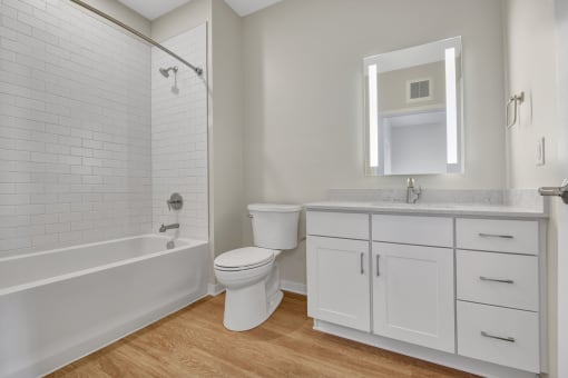 a bathroom with white cabinets and a white bathtub