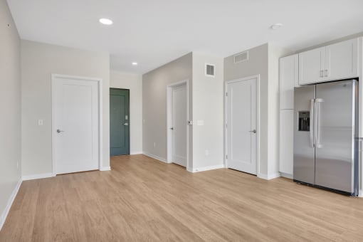 a bedroom with a medium sized bed and a refrigerator in a room with a hardwood floor