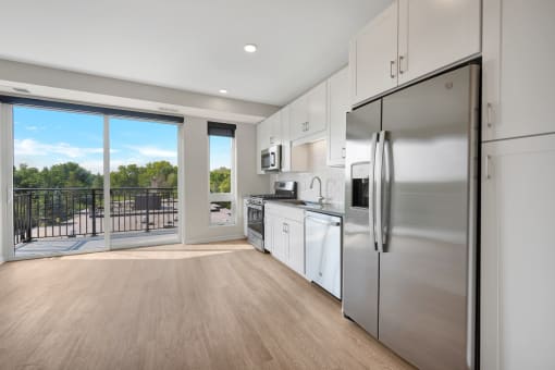 a kitchen with white cabinets and stainless steel appliances and a sliding glass door that leads to a
