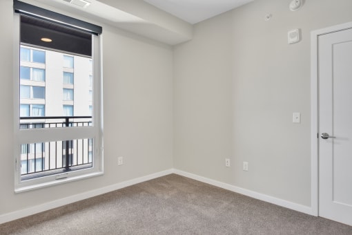 a bedroom with a large window and carpeted flooring